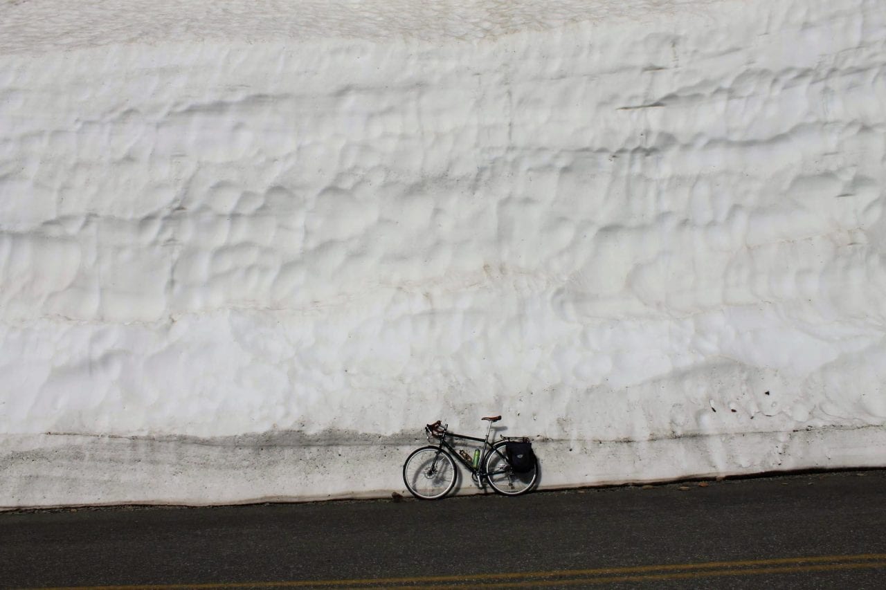 Bike against snowbank Glacier National Park photo via Brian Schott