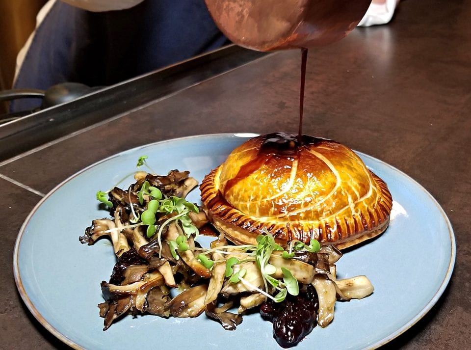 Venison Pie with Pan seared mushrooms and red wine jus being poured on