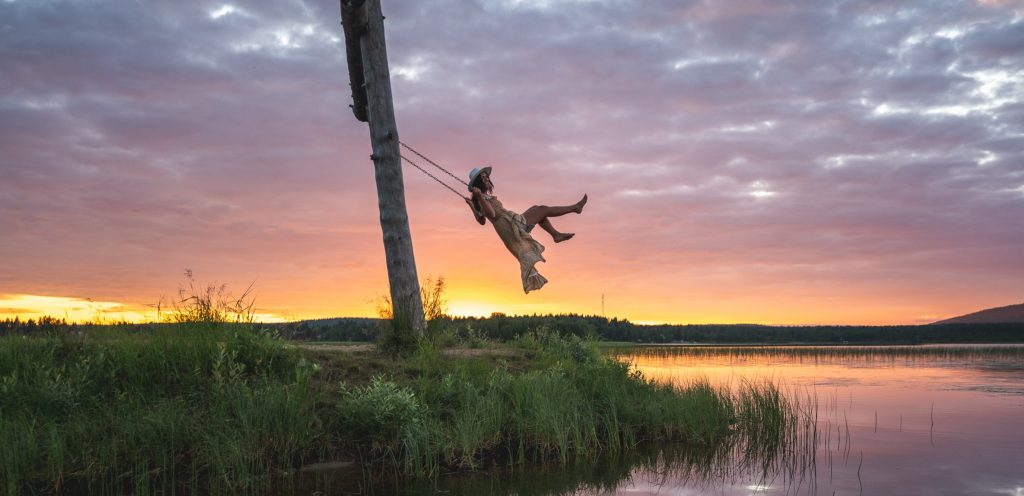 Girl on a swing under the midnight sun image taken by Eetu Leikas