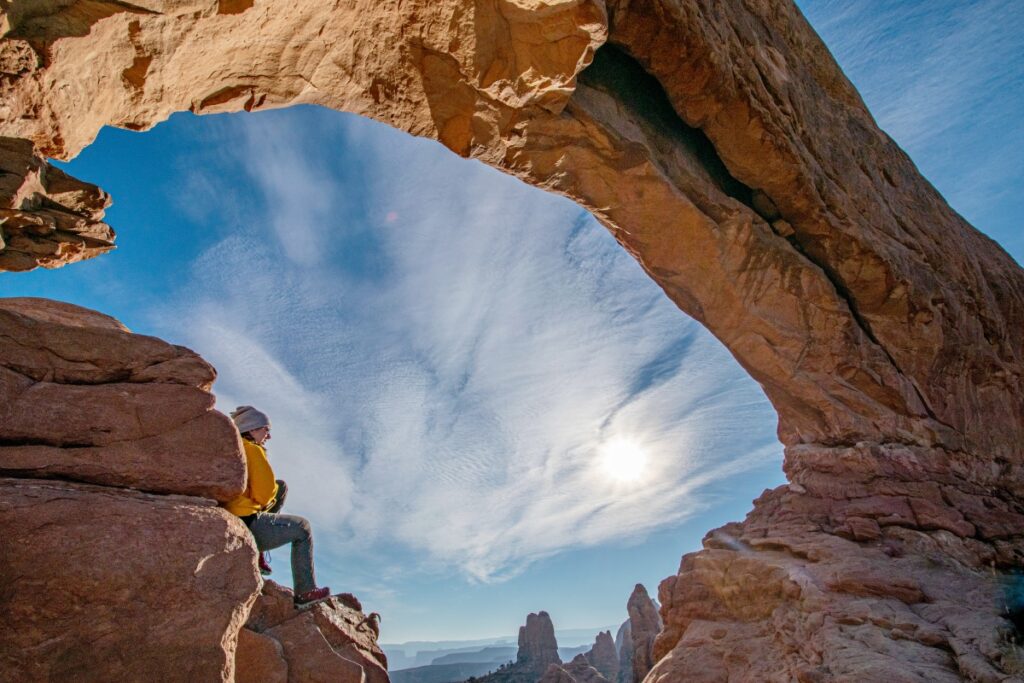 Girl sitting under Arch at Arches NP