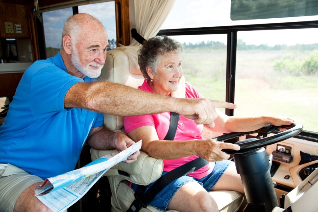 Senior couple traveling in their motor home. The husband is giving directions to the wife.