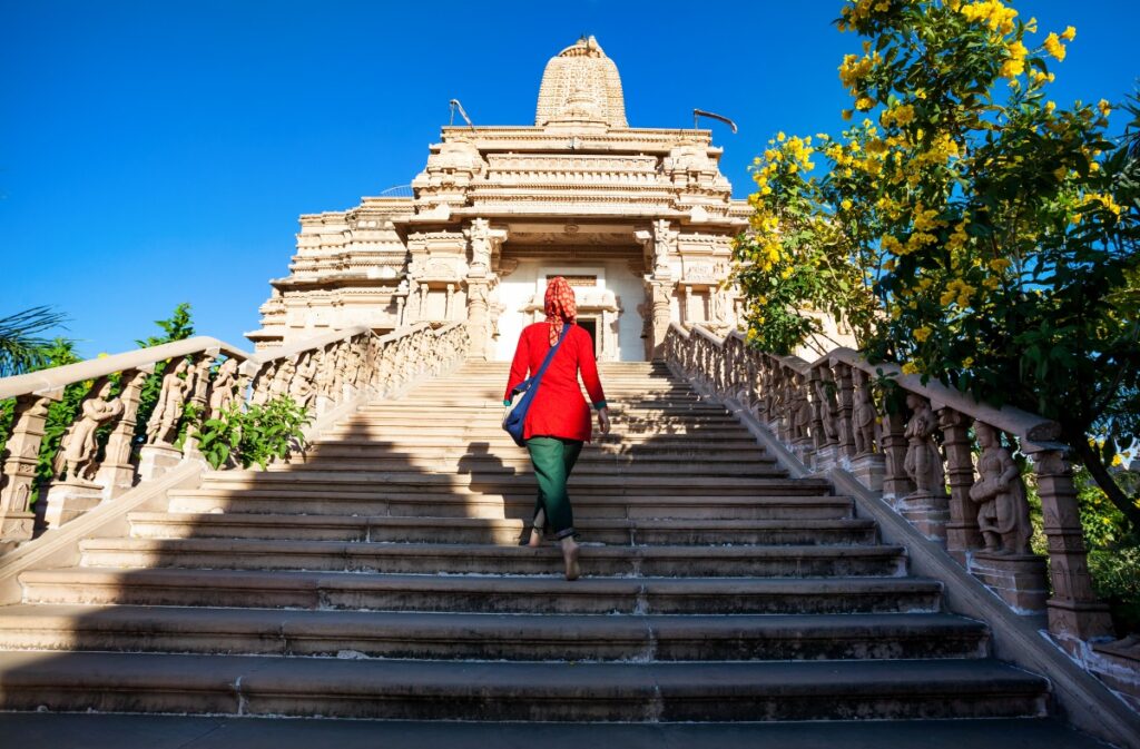 Indian woman in red dress on the stairs of Jain temple in Nasik, Maharashtra, India