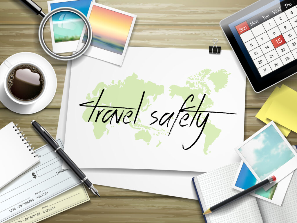 top view of travel items on wooden table with travel safety written on paper