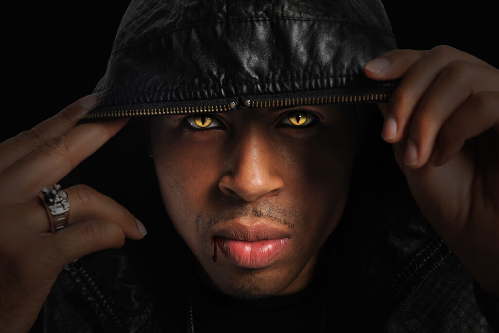Portrait of African American vampire with hood over head with strong directional light