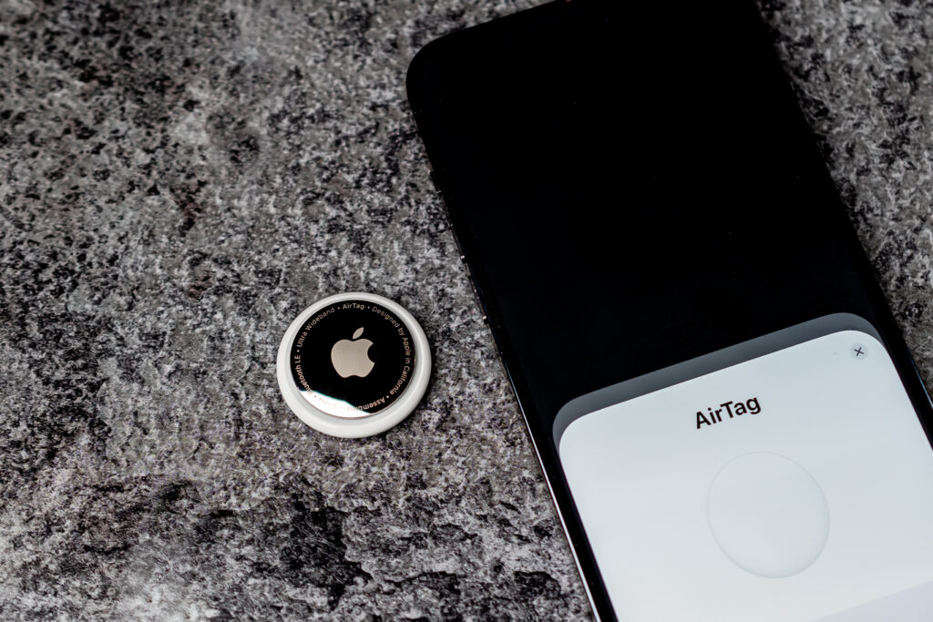 AirTag Apple lies on table nex to smartphone witch are connected to tag. Air Tag gadget to track of your stuff. 