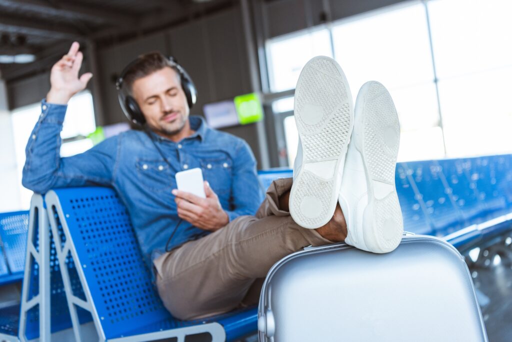 Man relaxing at airport with travel tech