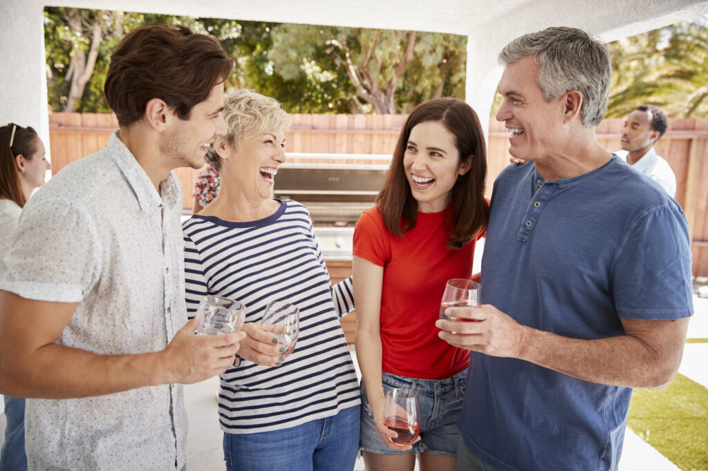 Parents and adult children standing with drinks in garden