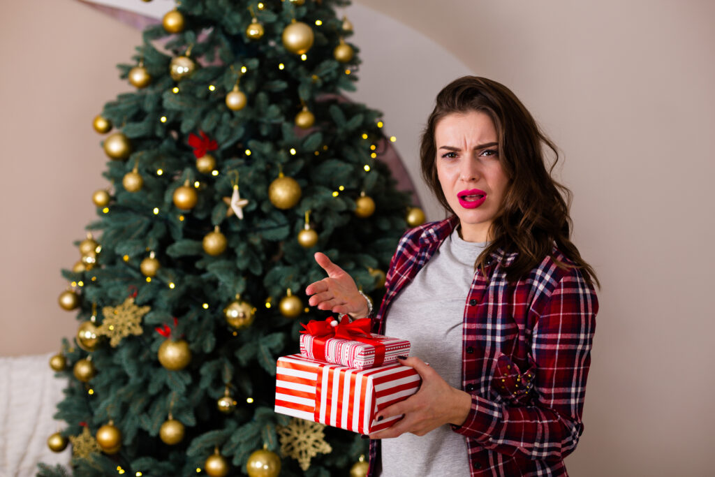 Beautiful woman with presents standing near the Christmas tree