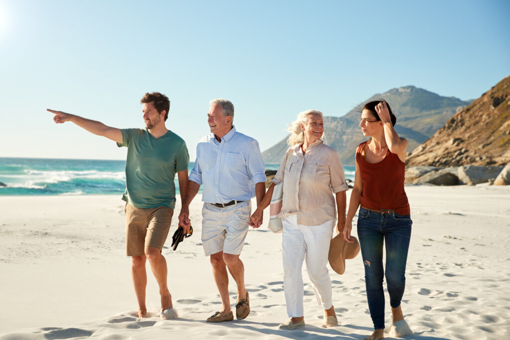 Middle-aged and older white couples walking on the beach together and talking full length in close-up