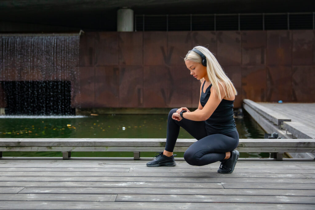 Fitness woman using smart watch phone. Tracking fitness application technology, listen music. Healthy joyful sporty lifestyle.