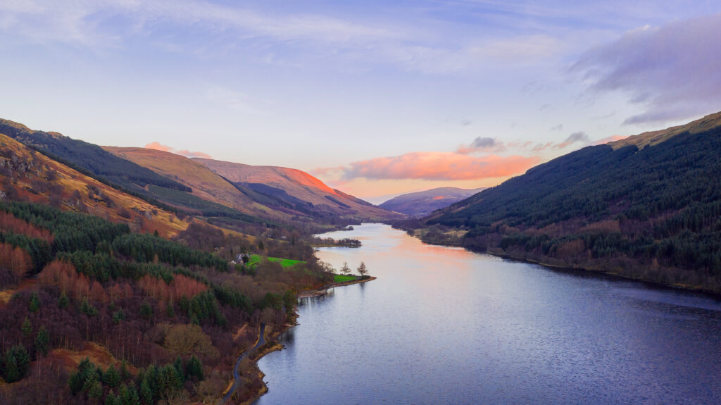 Scottish beautiful colorful sunset landscape with Loch Voil, mountains and forest at Loch Lomond & The Trossachs National Park. Nature evening scenery in Scotland over the mountain lake.